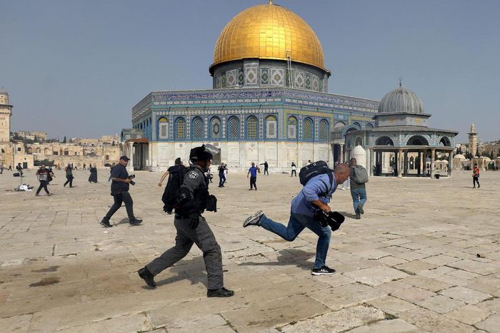A member of Israeli police runs after a cameraman during clashes with Palestinians at the compound that houses Al-Aqsa Mosque, known to Muslims as Noble Sanctuary and to Jews as Temple Mount, in Jerusalem's Old City, May 10, 2021.