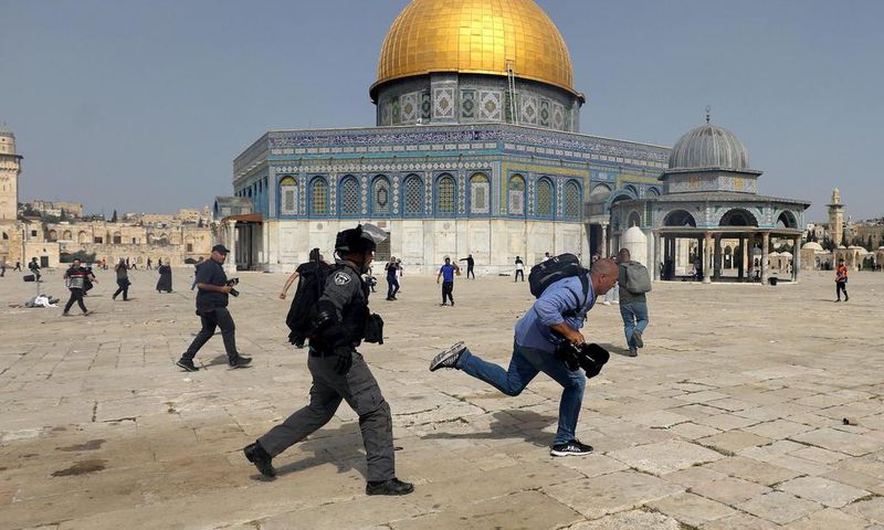 A member of Israeli police runs after a cameraman during clashes with Palestinians at the compound that houses Al-Aqsa Mosque, known to Muslims as Noble Sanctuary and to Jews as Temple Mount, in Jerusalem's Old City, May 10, 2021.