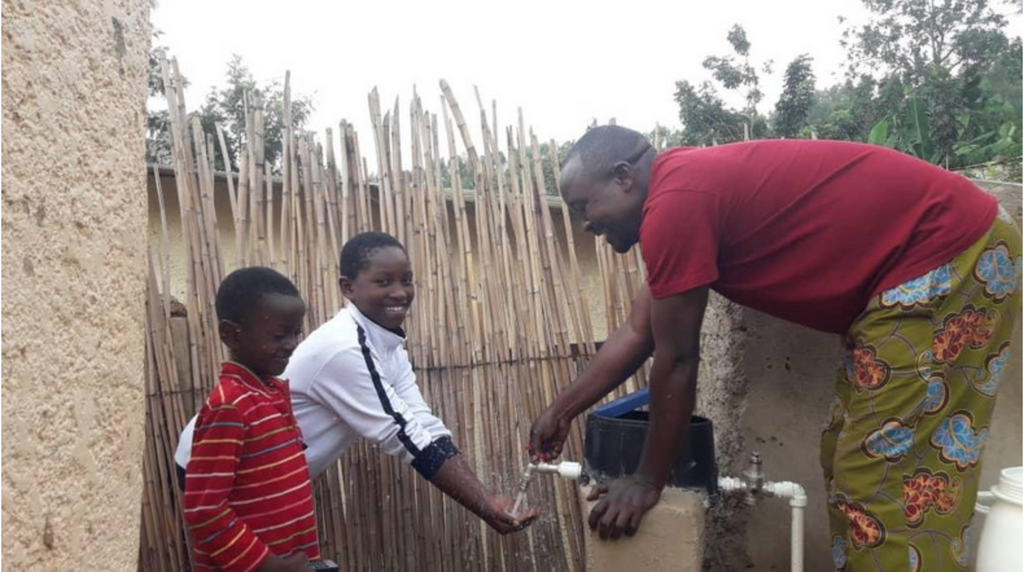 Une famille au Rwanda teste avec plaisir la pompe à eau nouvellement installée dans son complexe. Source: Water Access Rwanda