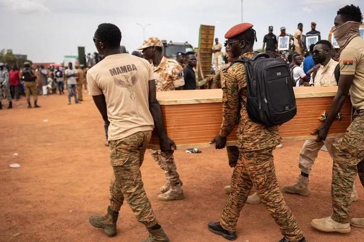 Des militaires burkinabés portent un cercueil lors de l'enterrement des 27 soldats tués alors qu'ils escortaient 207 véhicules dans un convoi à Gaskinde