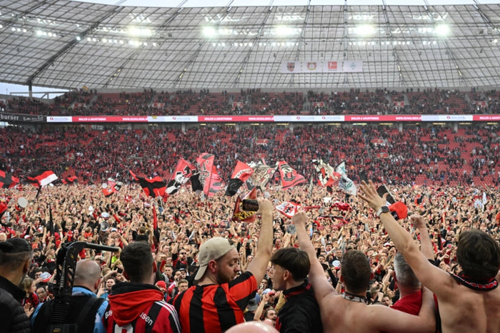 Les supporters du Bayer Leverkusen exultent sur la pelouse de la BayArena après le sacre de leur équipe en championnat d'Allemagne, le 14 avril 2024  AFP INA FASSBENDER