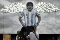 Des fresques murales à Buenos Aires montrent Maradona portant des ailes d'ange, embrassant la Coupe du monde / AFP