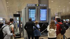 Travelers look at a departures board at Tel Aviv airport on October 7 as dozens of flights get canceled.Gil Cohen-Magen/AFP via Getty Images