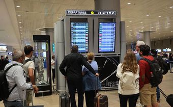 Travelers look at a departures board at Tel Aviv airport on October 7 as dozens of flights get canceled.Gil Cohen-Magen/AFP via Getty Images