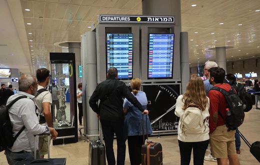 Travelers look at a departures board at Tel Aviv airport on October 7 as dozens of flights get canceled.Gil Cohen-Magen/AFP via Getty Images