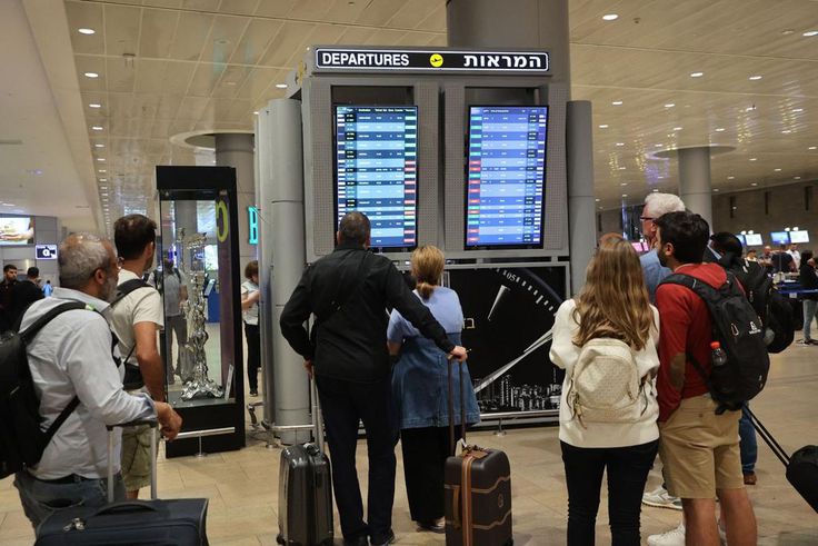 Travelers look at a departures board at Tel Aviv airport on October 7 as dozens of flights get canceled.Gil Cohen-Magen/AFP via Getty Images