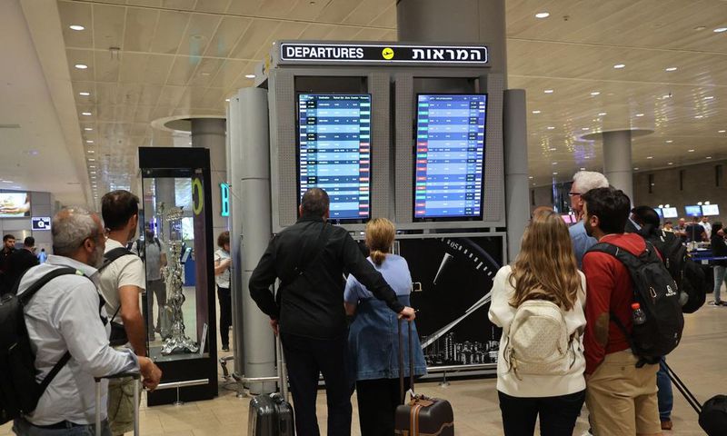 Travelers look at a departures board at Tel Aviv airport on October 7 as dozens of flights get canceled.Gil Cohen-Magen/AFP via Getty Images