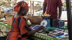 Une femme sur un marché de Dakar traite une commande de légumes à l’aide de sa tablette Weebi © Vincent Tremeau - La Banque mondiale