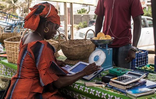 Une femme sur un marché de Dakar traite une commande de légumes à l’aide de sa tablette Weebi © Vincent Tremeau - La Banque mondiale