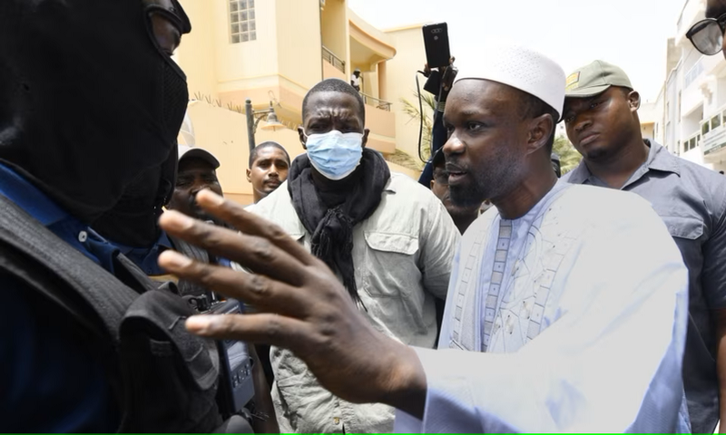 L'opposant sénégalais Ousmane Sonko discute avec des membres de la police devant sa résidence à Dakar, le 17 juin 2022.