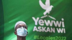 Ousmane Sonko devant une banderole avec le logo de la coalition Yewwi Askanwi