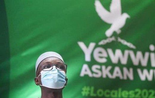Ousmane Sonko devant une banderole avec le logo de la coalition Yewwi Askanwi