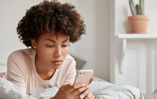 image-jeune-femme-noire-coupe-cheveux-afro-verifie-nouvelle-mise-jour-reseaux-sociaux-partage-fichiers-multimedias-son-telephone-portable-vetue-vetements-nuit-decontractes-se-repose-dans-son-lit-effectue-p