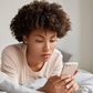 image-jeune-femme-noire-coupe-cheveux-afro-verifie-nouvelle-mise-jour-reseaux-sociaux-partage-fichiers-multimedias-son-telephone-portable-vetue-vetements-nuit-decontractes-se-repose-dans-son-lit-effectue-p