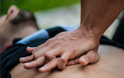 Un homme se trouve à plat pendant que quelqu’un fait la RCR sur sa poitrine nue