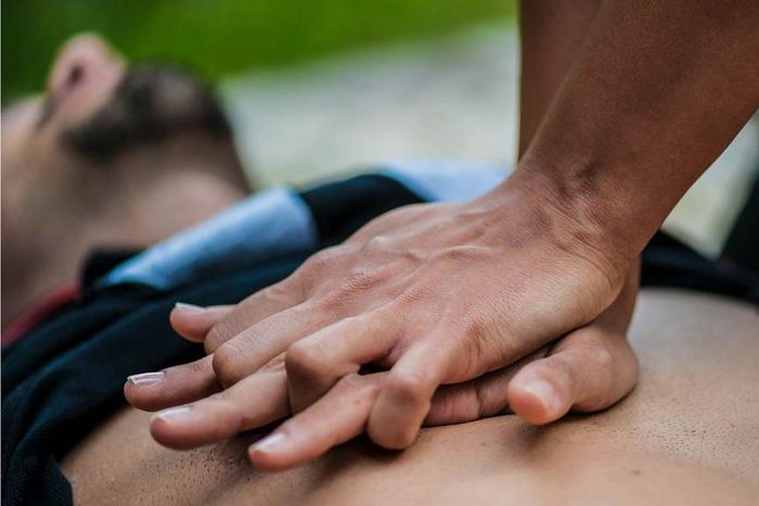 Un homme se trouve à plat pendant que quelqu’un fait la RCR sur sa poitrine nue