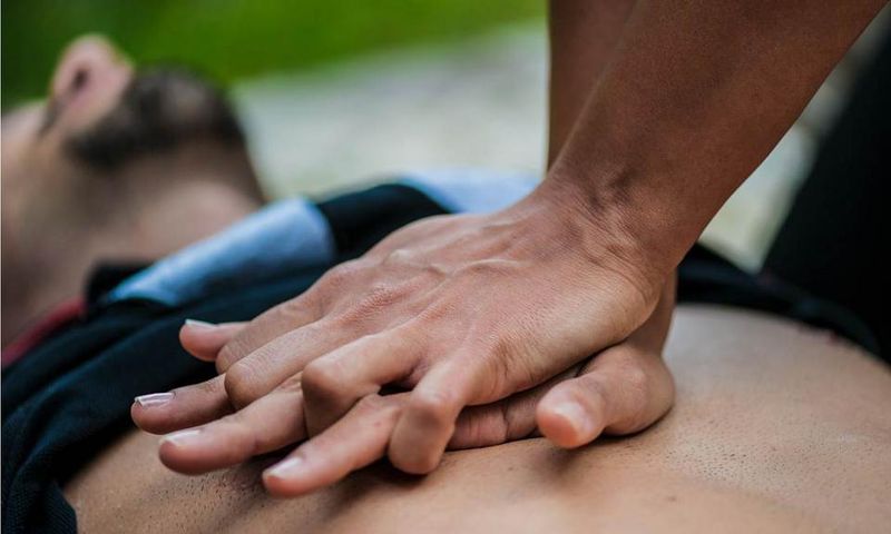 Un homme se trouve à plat pendant que quelqu’un fait la RCR sur sa poitrine nue