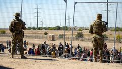 Migrants wait in line adjacent to the border fence under the watch of the Texas National Guard to enter into El Paso, Texas, May 10, 2023.Andres Leighton/AP Photo