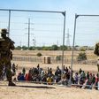 Migrants wait in line adjacent to the border fence under the watch of the Texas National Guard to enter into El Paso, Texas, May 10, 2023.Andres Leighton/AP Photo