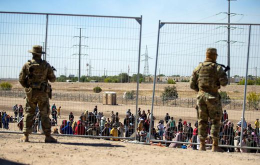 Migrants wait in line adjacent to the border fence under the watch of the Texas National Guard to enter into El Paso, Texas, May 10, 2023.Andres Leighton/AP Photo