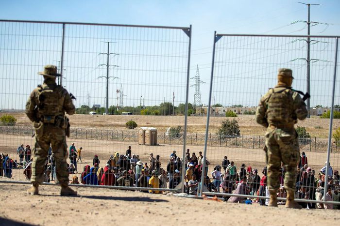 Migrants wait in line adjacent to the border fence under the watch of the Texas National Guard to enter into El Paso, Texas, May 10, 2023.Andres Leighton/AP Photo