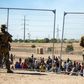 Migrants wait in line adjacent to the border fence under the watch of the Texas National Guard to enter into El Paso, Texas, May 10, 2023.Andres Leighton/AP Photo