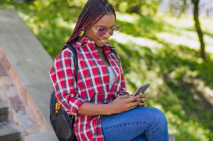 une fille-noire-regardant-telephone-dans-parc 23-2147664313