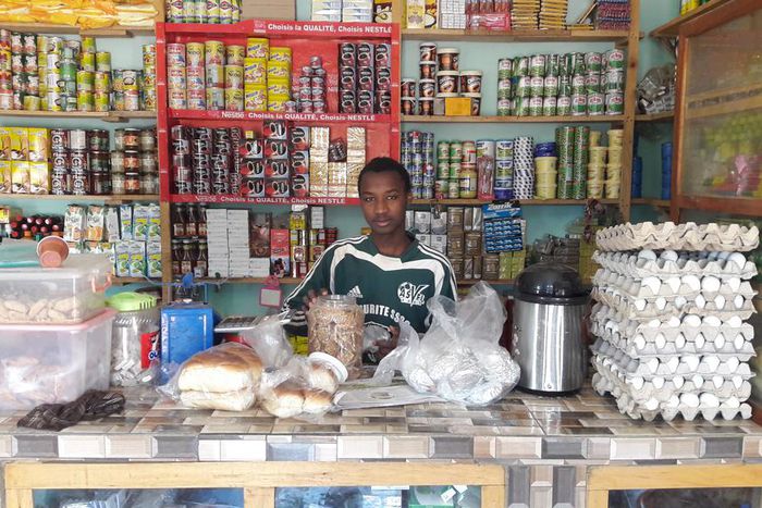Un jeune vendeur debout au comptoir dans une boutique (image d'illustration)