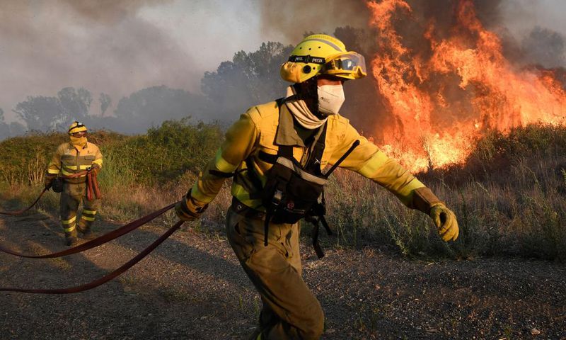 Firefighters try to extinguish a wildfire next to the village of Tabara, near Zamora, northern Spain, on Monday.