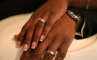 A stock photo of a couple showing off their wedding rings.