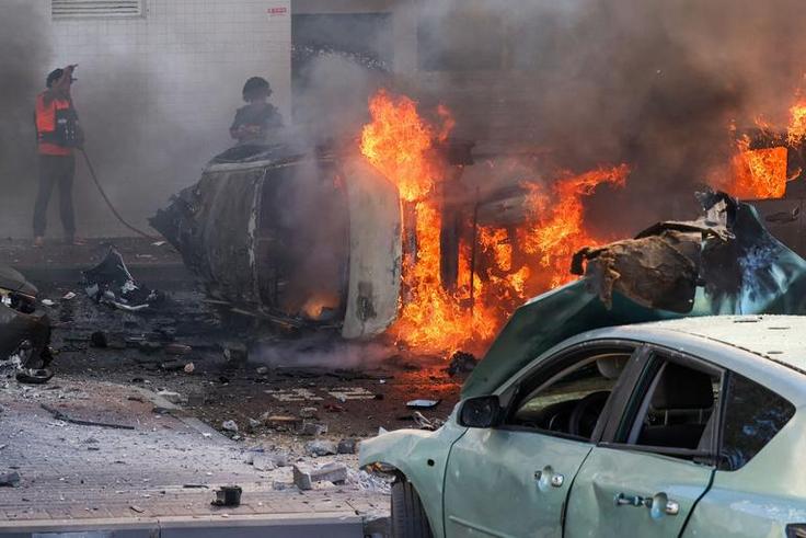 People try to extinguish a fire in Ashkelon, Israel, after Hamas launched a series of surprise attacks on October 7.Ahmad Gharabli/AFP via Getty Images