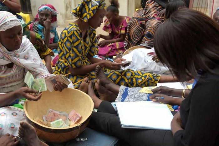 Des femmes comptent l'argent pour la cagnotte de la tontine