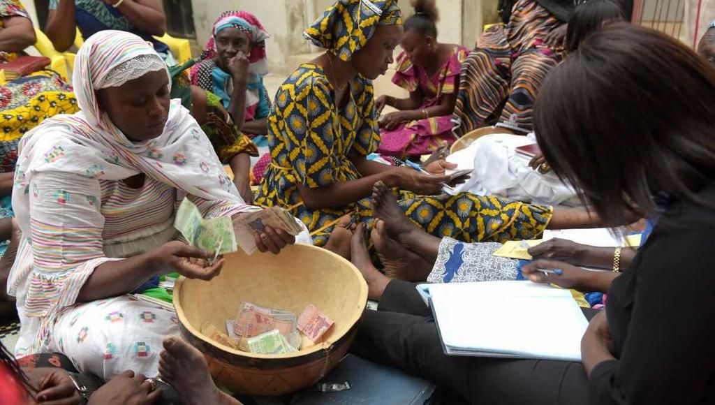 Des femmes comptent l'argent pour la cagnotte de la tontine