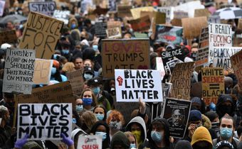 Protesters hold placards as they attend a demonstration in Parliament Square in central London on June 6, 2020, to show solidarity with the Black Lives Matter movement in the wake of the killing of George Floyd, an unarmed black man who died after a po...