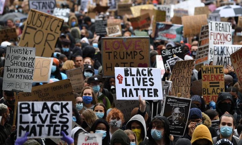 Protesters hold placards as they attend a demonstration in Parliament Square in central London on June 6, 2020, to show solidarity with the Black Lives Matter movement in the wake of the killing of George Floyd, an unarmed black man who died after a po...