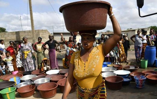 An Ivorian woman carries a heavy load after a distribution of safe drinking water in Bouake in early June