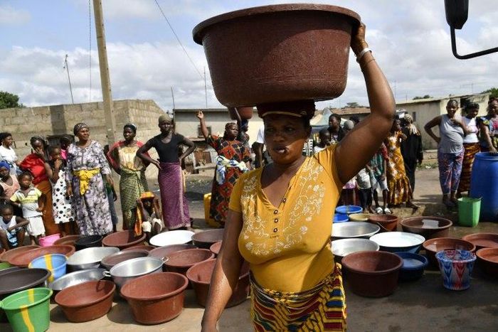 An Ivorian woman carries a heavy load after a distribution of safe drinking water in Bouake in early June