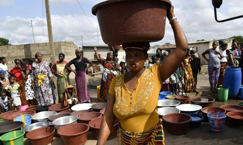 An Ivorian woman carries a heavy load after a distribution of safe drinking water in Bouake in early June