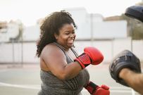 femme-africaine-curvy-et-entraîneur-personnel-faire-de-la-boxe-séance-d-entraînement-extérieur-focus-sur-le-visage-african-220749623