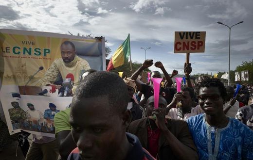 Supporters of the junta, which calls itself the CNSP (National Committee for the Salvation of the People), walk past a banner depicting its leader Assimi Goita in a rally in Bamako on Wednesday