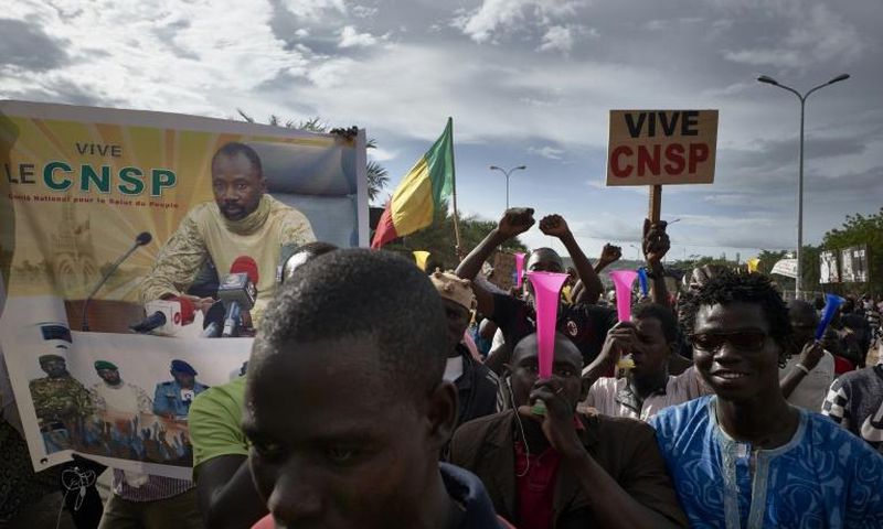 Supporters of the junta, which calls itself the CNSP (National Committee for the Salvation of the People), walk past a banner depicting its leader Assimi Goita in a rally in Bamako on Wednesday