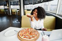 Une femme mange une pizza dans un restaurant (illustration)