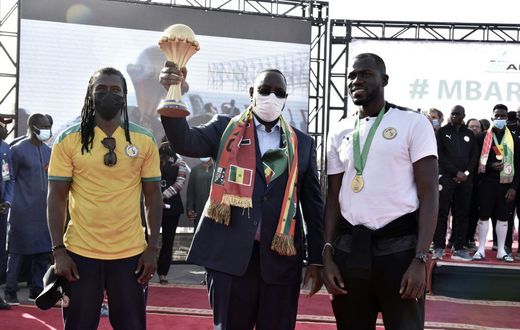 Senegal President Macky Sall holds the Africa Cup of Nations trophy flanked by coach Cisse and skipper  Kalidou Koubaly