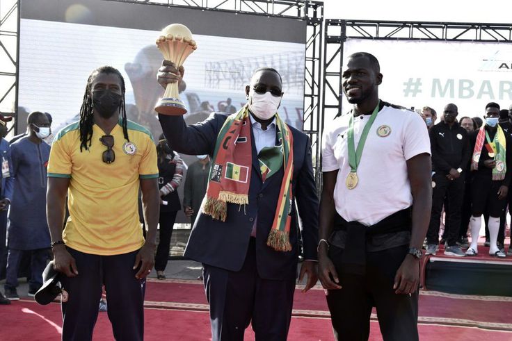 Senegal President Macky Sall holds the Africa Cup of Nations trophy flanked by coach Cisse and skipper  Kalidou Koubaly