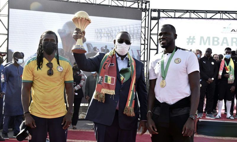 Senegal President Macky Sall holds the Africa Cup of Nations trophy flanked by coach Cisse and skipper  Kalidou Koubaly