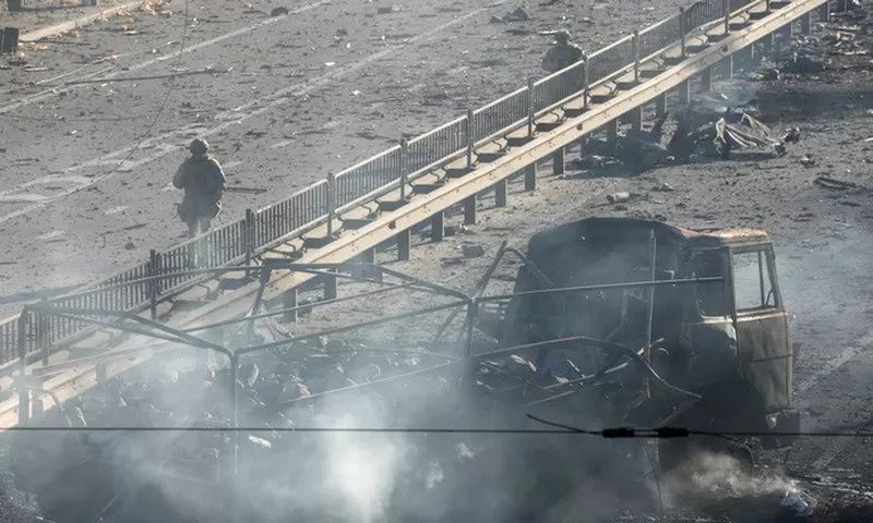 Soldat ukrainier passant à côté des débris d'un camion militaire dans la rue à Kiev - Samedi