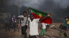 An anti-coup protester holds a Burkinabe flag in Ouagadougou, Burkina Faso, September 18, 2015. Leaders of a coup in Burkina Faso said on Friday they had freed the president and reopened borders, in an apparent olive branch to mediators and protesters ...