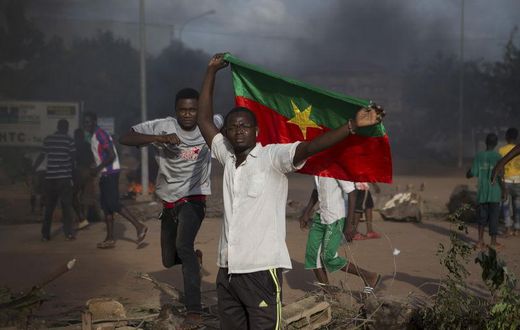 An anti-coup protester holds a Burkinabe flag in Ouagadougou, Burkina Faso, September 18, 2015. Leaders of a coup in Burkina Faso said on Friday they had freed the president and reopened borders, in an apparent olive branch to mediators and protesters ...