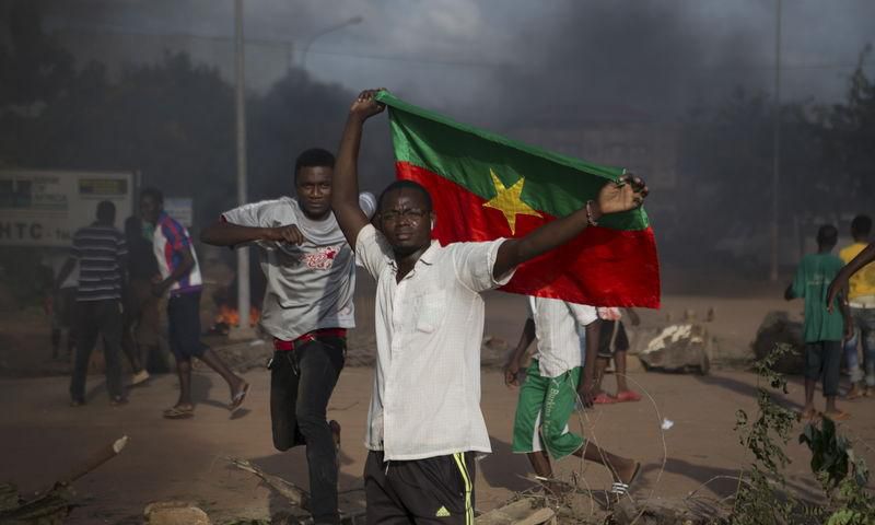 An anti-coup protester holds a Burkinabe flag in Ouagadougou, Burkina Faso, September 18, 2015. Leaders of a coup in Burkina Faso said on Friday they had freed the president and reopened borders, in an apparent olive branch to mediators and protesters ...