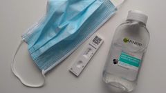 A face mask, a positive COVID-19 test, and a bottle of sanitizer.
